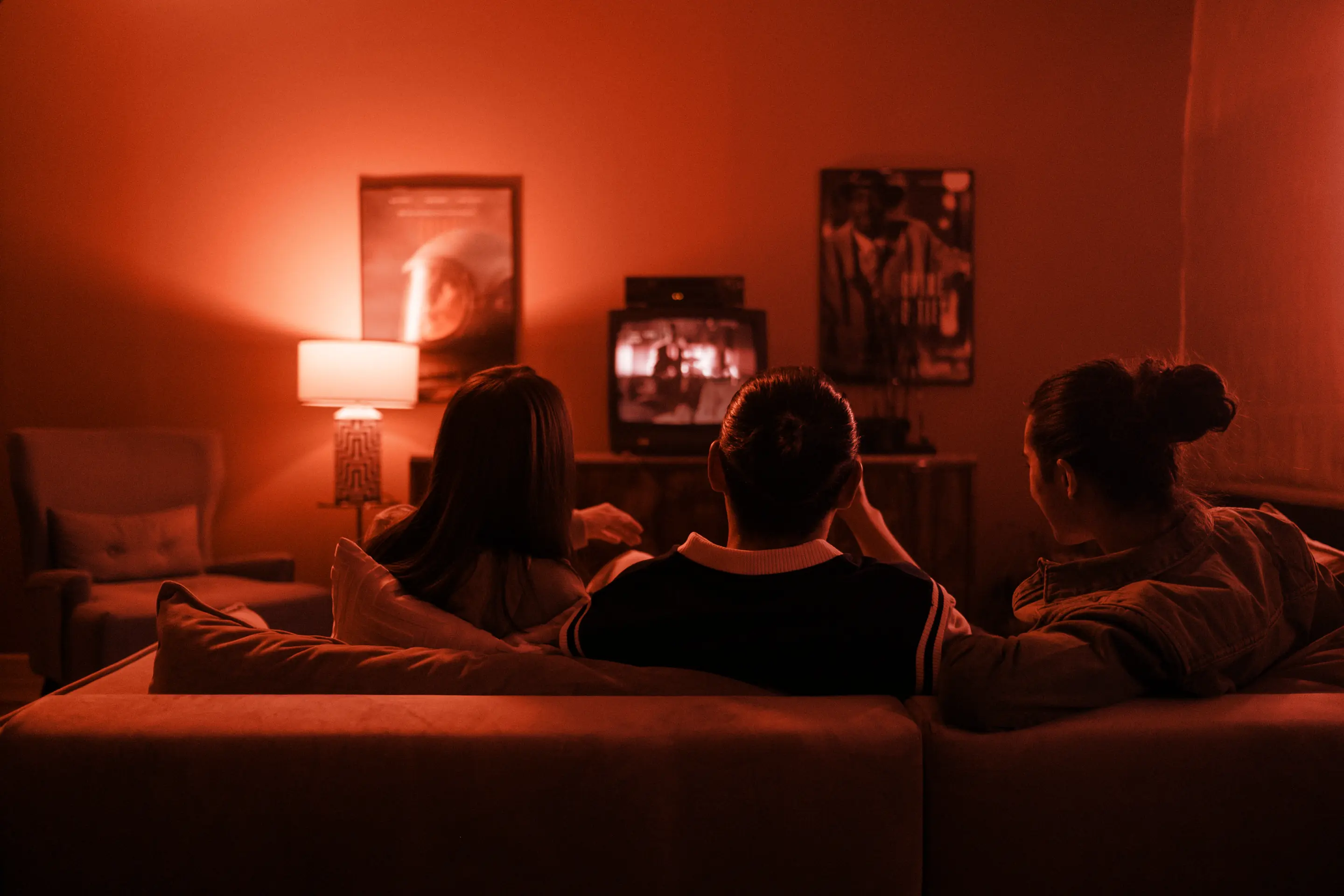 Friends on a sofa in a warm living room, watching the TV