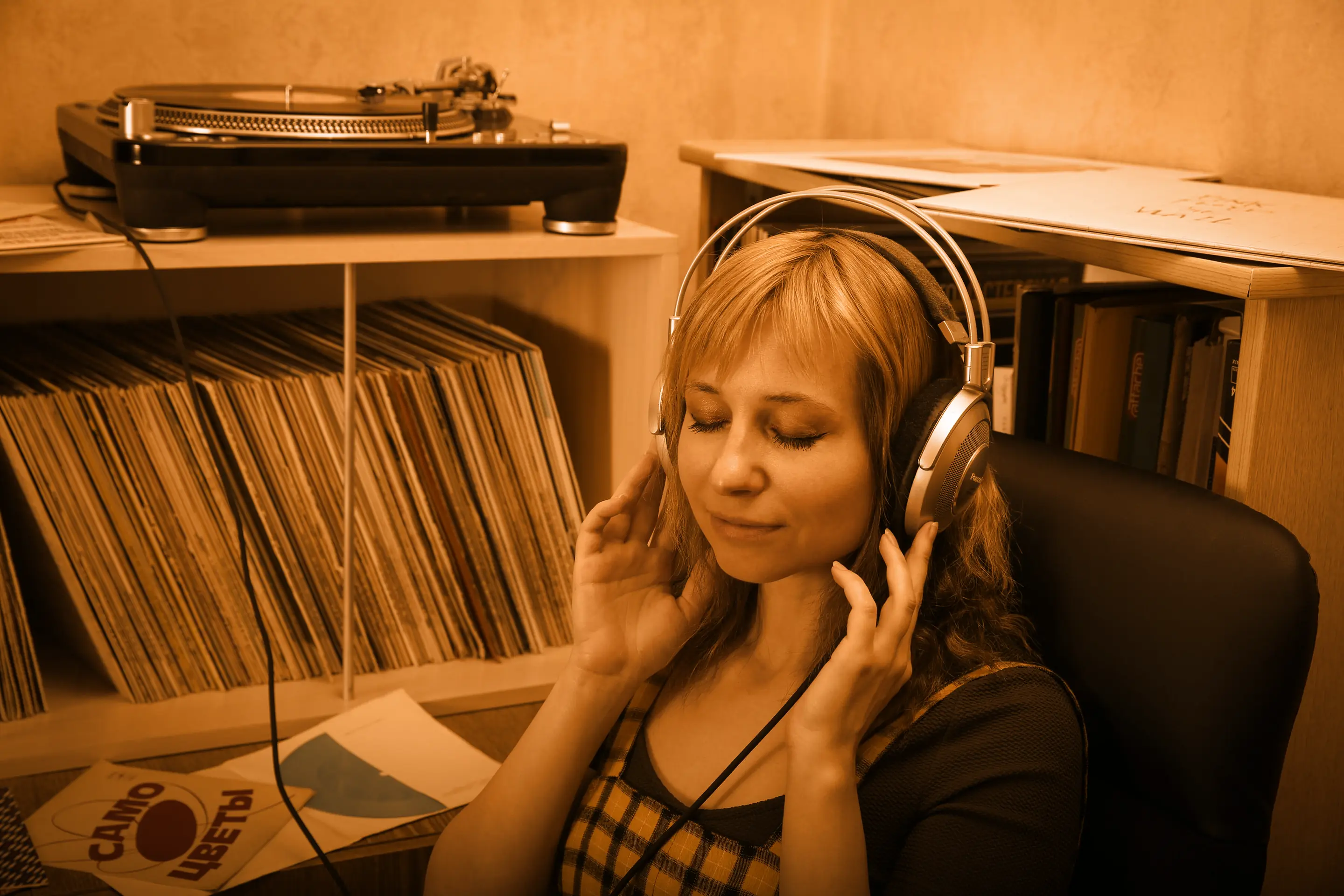 A woman listening on headphones in front of her record collection